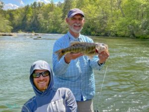 Jimmy Harris, co-owner of Unicoi Outfitters, prepares to release a 20-plus inch shoal bass with Wes McElroy. – Rusty Chinnis | Sun