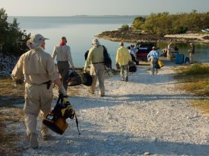 Anglers walk down to a boat to go fishing.