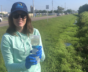 Woman Abbey Tyrna holding a jar of water in a field.