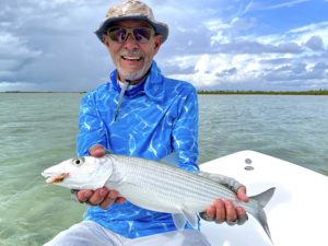 Man on boat holding big fish he has caught.